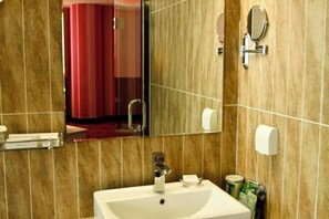 Un baño con lavamanos, espejo y perchero para toallas.
