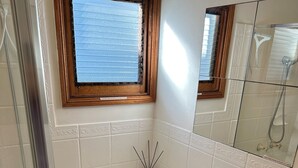 A bathroom with a white sink, a mirror, a towel rack, and a shower area.
