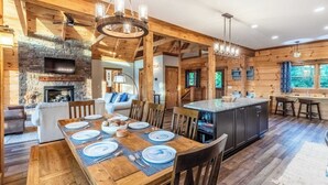 A spacious wooden cabin interior with a dining area, kitchen, and living space. - Luxury Cabin: Lake view/access, Theater, Game room (Bryson City)