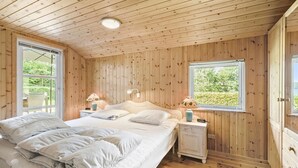 A wooden-paneled bedroom with a bed, bedside tables, and two windows. - Awesome home in Ry with WiFi (Ry)