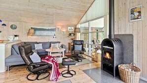 A cozy living room with a fireplace, wooden walls, and a large window. - Awesome home in Ry with WiFi (Ry)