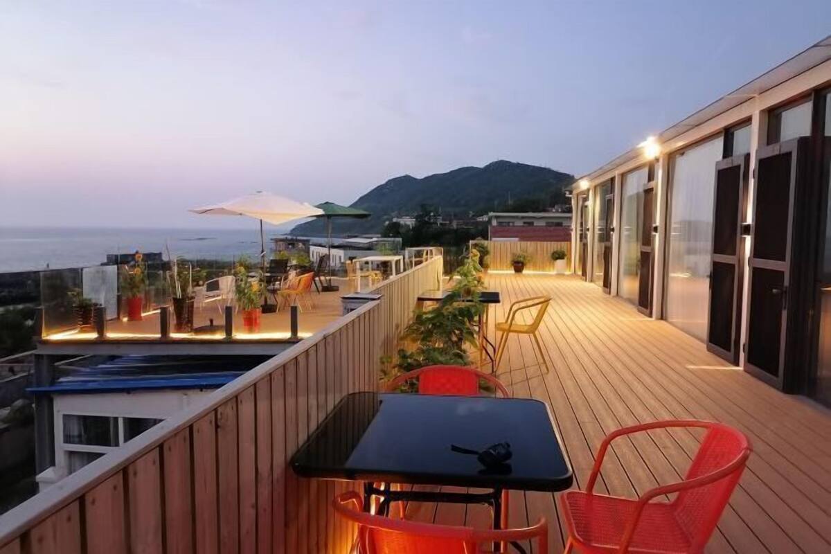 Una terraza en la azotea con mobiliario exterior, piscina y vistas al mar.
