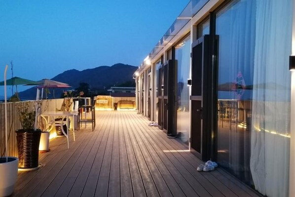 A wooden deck with outdoor seating and a view of the sea.