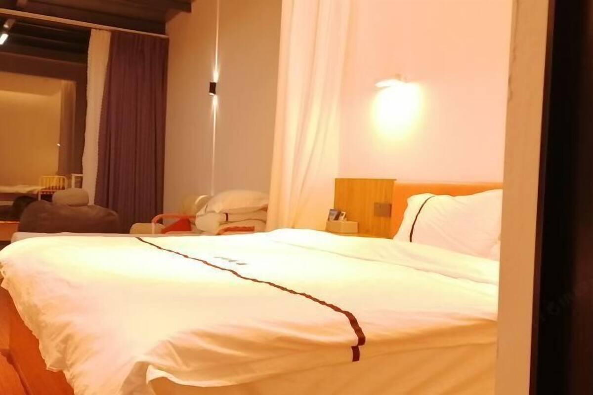 Una habitación de hotel con cama, mesita de noche, lámpara y espejo.