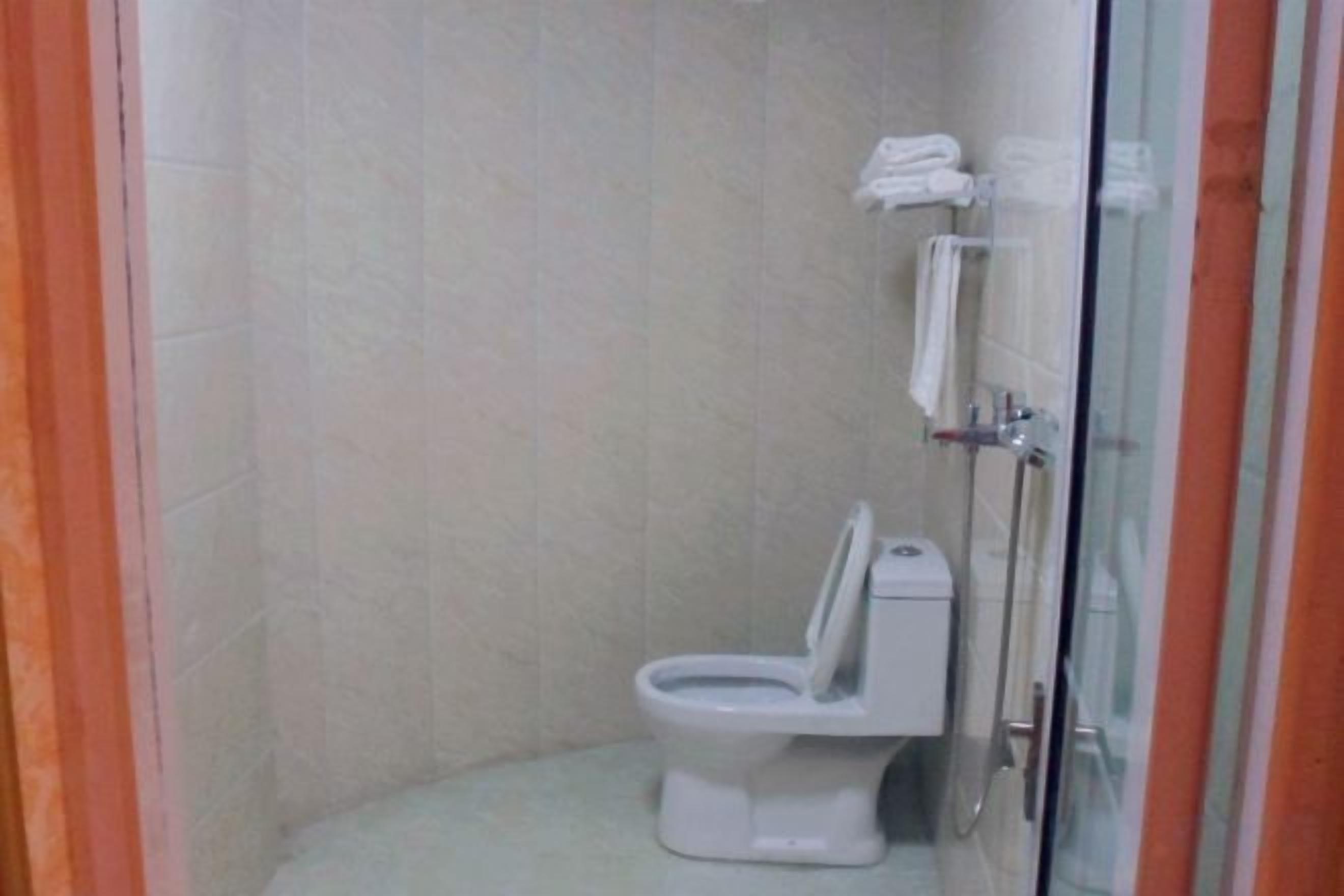 A bathroom with a toilet, a glass shower enclosure, and a towel rack.