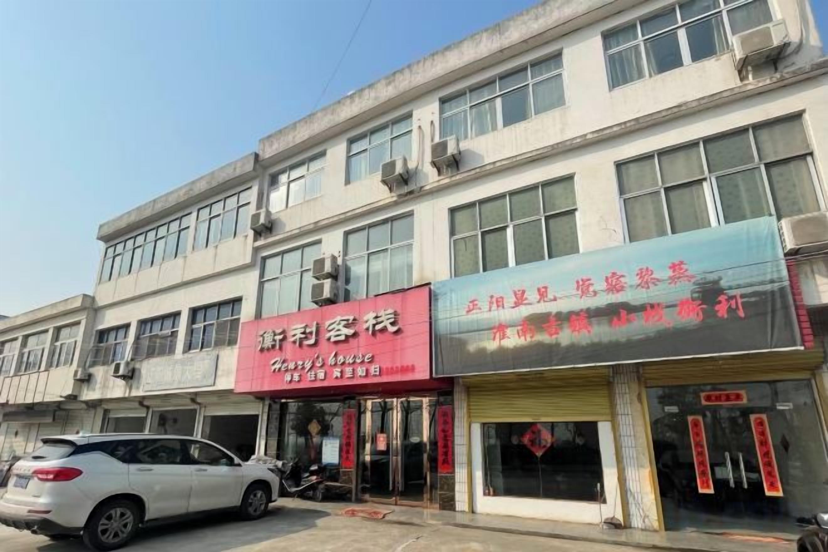 A building with multiple storefronts, including a visible sign for a business named 'Shengli Qiao' and another sign for 'Xiaojiu'.