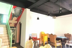 A room with a staircase, a wall with a mural, and several chairs and tables. - Left-hand hostel in Xichong,shenzhen (Shenzhen)
