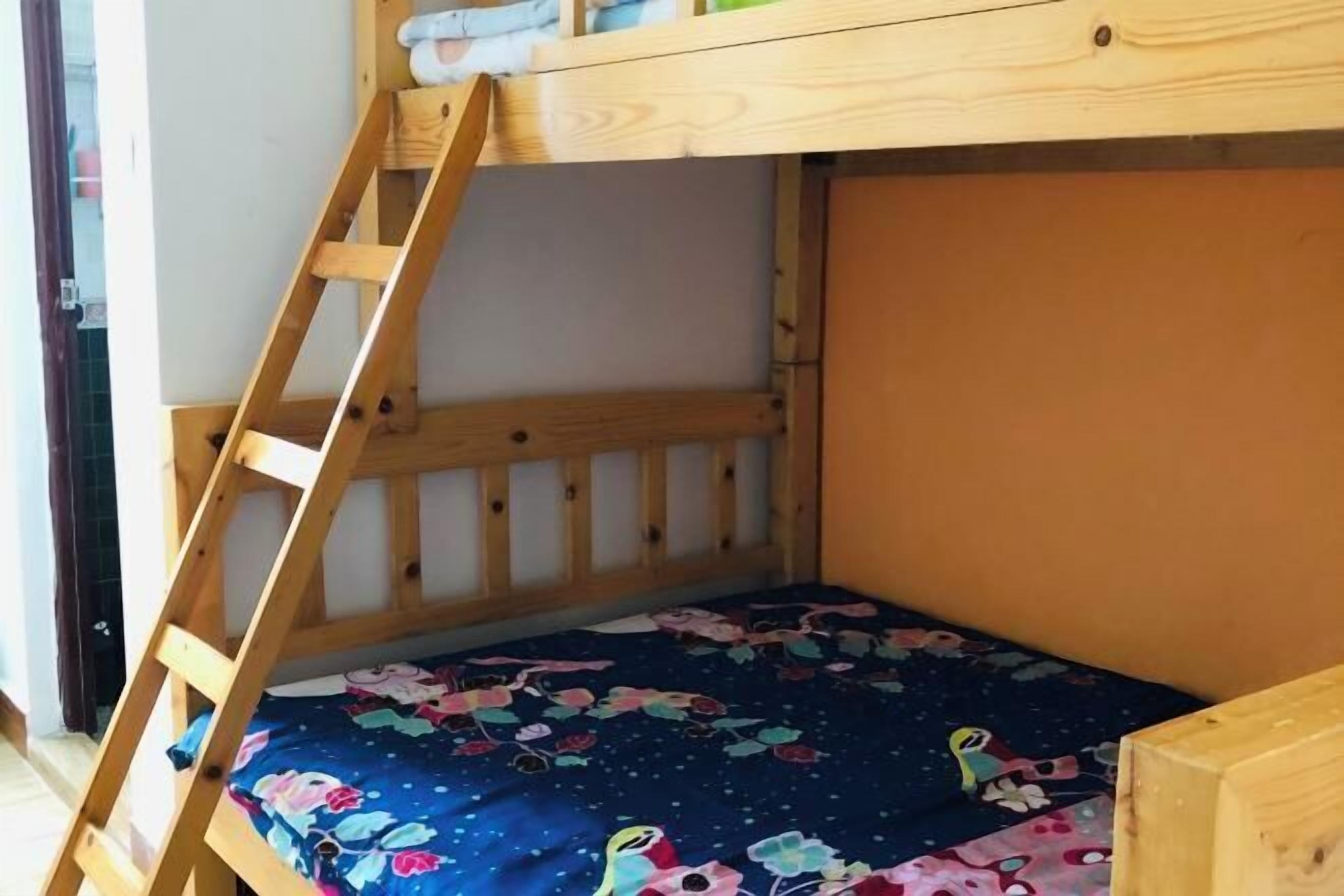A bunk bed with a wooden ladder and a floral-patterned bedspread.