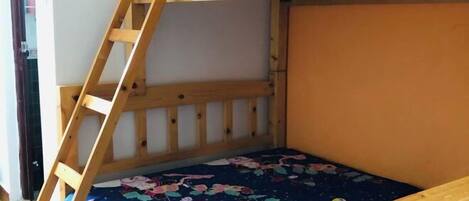 A bunk bed with a wooden ladder and a floral-patterned bedspread.