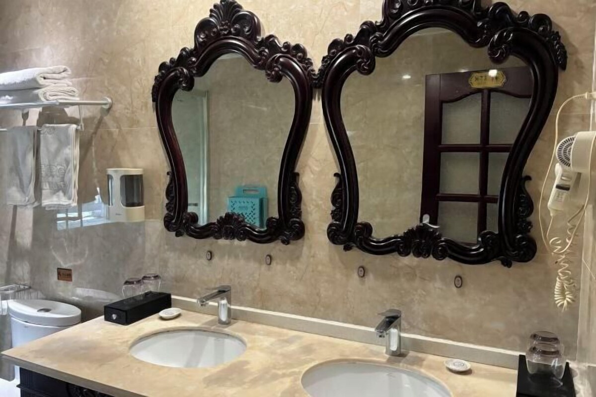 Un baño con dos lavamanos, un espejo y un secador de pelo.