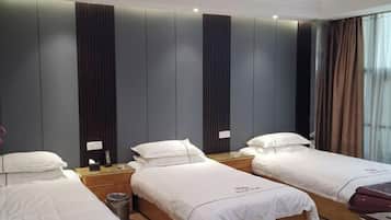 A hotel room with three single beds, a wooden nightstand, a trash bin, and a window with curtains.