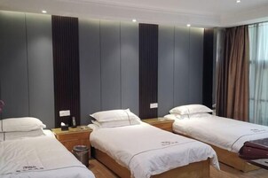 Habitación de hotel con tres camas individuales, una mesita de noche de madera, un cesto de basura y una ventana con cortinas.