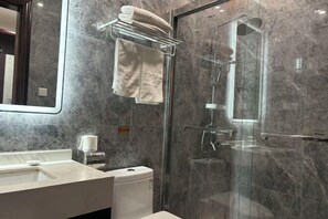 Un baño moderno con ducha envuelta en vidrio, pared de mármol y un perchero.