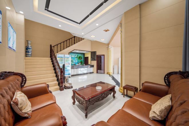 A hotel lobby with a staircase, leather sofas, a coffee table, and a reception desk.
