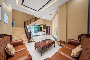A hotel lobby with a staircase, leather sofas, a coffee table, and a reception desk. - TaoranjuHotel (Xuzhou)