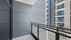 Um edifício moderno com varanda de vidro e vista para outros edifícios.
