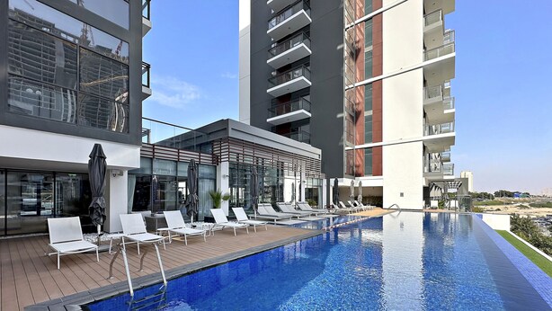 Um hotel moderno com piscina infinita no terraço, cadeiras de lounge e fachada de vidro.