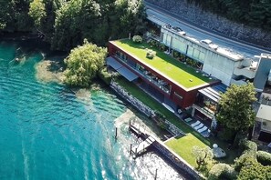 A modern building with a flat roof, a swimming pool, and a dock. - Maison Sur l'Eau (Paradiso)