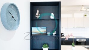 A modern kitchen with a built-in shelf unit containing decorative items, a wall clock, and a potted orchid. - Zen Gem Pool Private Balcony Oceanview (Darwin)