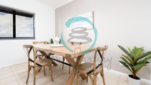 A dining area with a wooden table and chairs, a potted plant, and a window with blinds. - Zen Gem Pool Private Balcony Oceanview (Darwin)