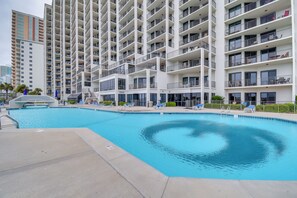 Un hôtel moderne doté d’une grande piscine, de nombreux balcons et offrant une vue sur les immeubles environnants.