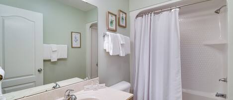 Une salle de bain équipée d’un lavabo, d’un miroir, de toilettes et d’une douche.