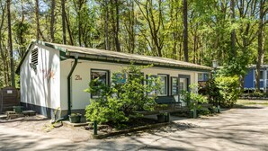 Eine kleine Hütte mit der Nummer 21a, umgeben von Bäumen und einer Bank.