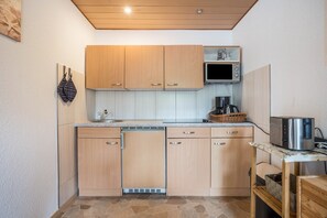 Una cocina compacta con armarios de madera, un microondas, un tostador y un lavavajillas.