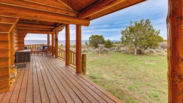 A wooden deck with a view of a grassy field and trees. - Spacious Rifle Cabin w/ Deck + Mountain Views! (Rifle)