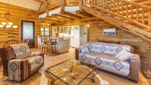A log cabin interior with a wooden staircase, a sofa, a coffee table, and a dining area. - Spacious Rifle Cabin w/ Deck + Mountain Views! (Rifle)