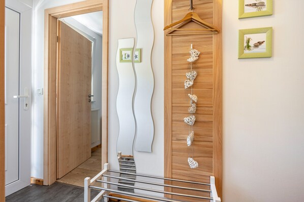 A hallway with a wooden door, a metal railing, and a wall-mounted decorative piece.