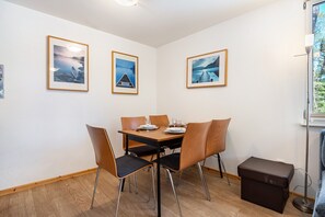 Een eetruimte met een tafel gedekt voor vier personen, ingelijste foto's aan de muur en een raam met uitzicht.
