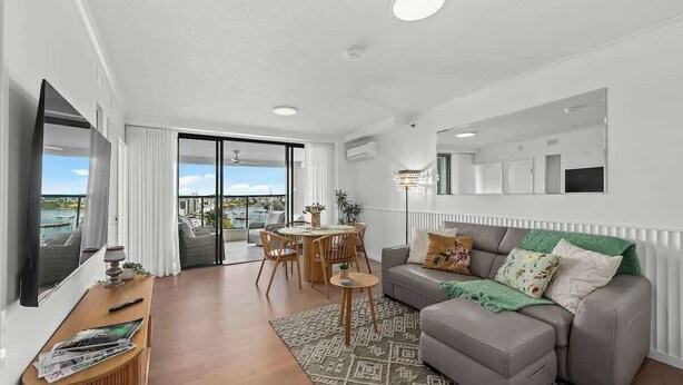 A modern living room with a grey sofa, a wooden coffee table, a dining area with a table and chairs, and a large window with a view. - Stunning! 2Bed, 1Bath, 1Car, VIEWS ~ CBD (Brisbane City)