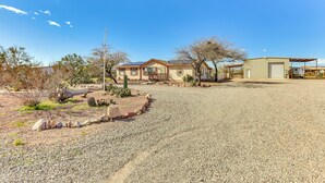 Ein Haus mit Kiesweg, Garage und kleinem Garten mit Kakteen und Steinen.