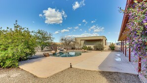 Ein Garten mit Schwimmbad, einer überdachten Terrasse und einem Haus mit rotem Dach.