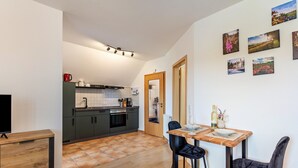 Une cuisine moderne avec des meubles de rangement sombres, une table à manger en bois et des chaises noires.