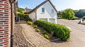 Une maison d’habitation avec une allée pavée, un mur en briques et un jardin bien entretenu.
