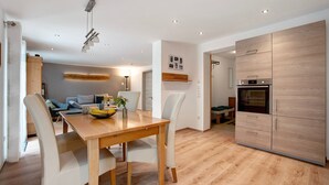 A modern kitchen with wooden cabinets, a built-in oven, and a dining area with a wooden table and chairs. - Apartment 'Ferienwohnung Birke' with Mountain View, Private Terrace and Wi-Fi (Altusried)