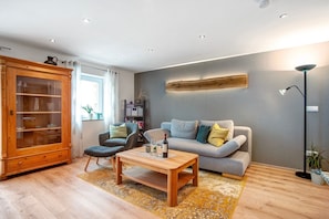 A living room with a wooden cabinet, a sofa, a coffee table, and a floor lamp. - Apartment 'Ferienwohnung Birke' with Mountain View, Private Terrace and Wi-Fi (Altusried)