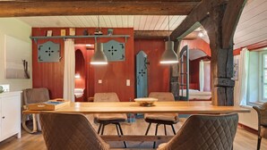 Un espace repas comprenant une table en bois, quatre chaises, des luminaires suspendus et un plafond en bois rustique.