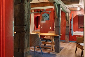 A rustic room with exposed wooden beams, a wooden table, and a chair. - Holiday Apartment 'Fewo 1 - "Blöck"' with Shared Garden and Wi-Fi (Oldenswort)