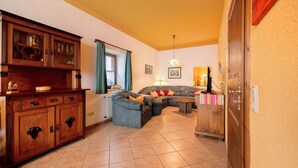 A living room with a sectional sofa, a wooden cabinet, and a dining area. - Apartment 'Eulennest 1' with Private Terrace and Wi-Fi (Minheim)