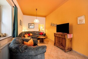 Una sala de estar con un conjunto de sofás, un televisor y un aparador de madera.