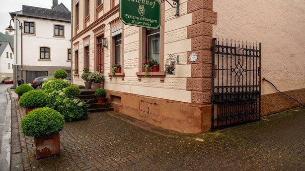 A building with a sign reading 'Eulenhof Ferienwohnungen Hubert Fielen' and a black wrought iron gate.
