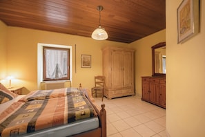 Un dormitorio con cama, armario de madera y ventana con cortinas.