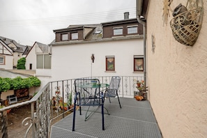 Un balcon avec une balustrade en métal, une table et deux chaises.