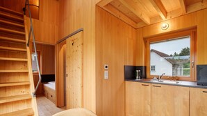Un interior de madera con una cocina, un ventanal y una escalera.