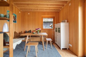 A wooden interior with a dining table, bench, and a white appliance.
