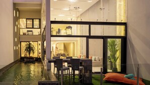 A modern interior with a dining area, a small pool, and a staircase leading to an upper level. - Master Peak H4 - 2BR Villa at Bang Rak Beach (Bo phut)