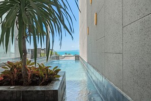 A pool area with a clear view of the ocean, a palm tree, and a stone wall. - Master Peak H4 - 2BR Villa at Bang Rak Beach (Bo phut)